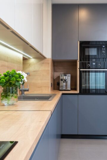 A modern countertop vacuum sealer sits on a marble island next to sealed vegetables.